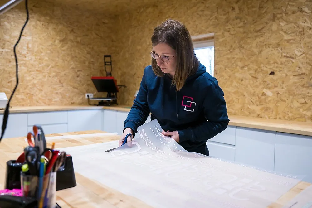 Découpe de transferts textiles à l'atelier, presse à chaud en arrière-plan